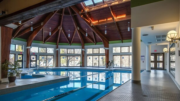 An indoor swimming pool with a high ceiling and large windows.
