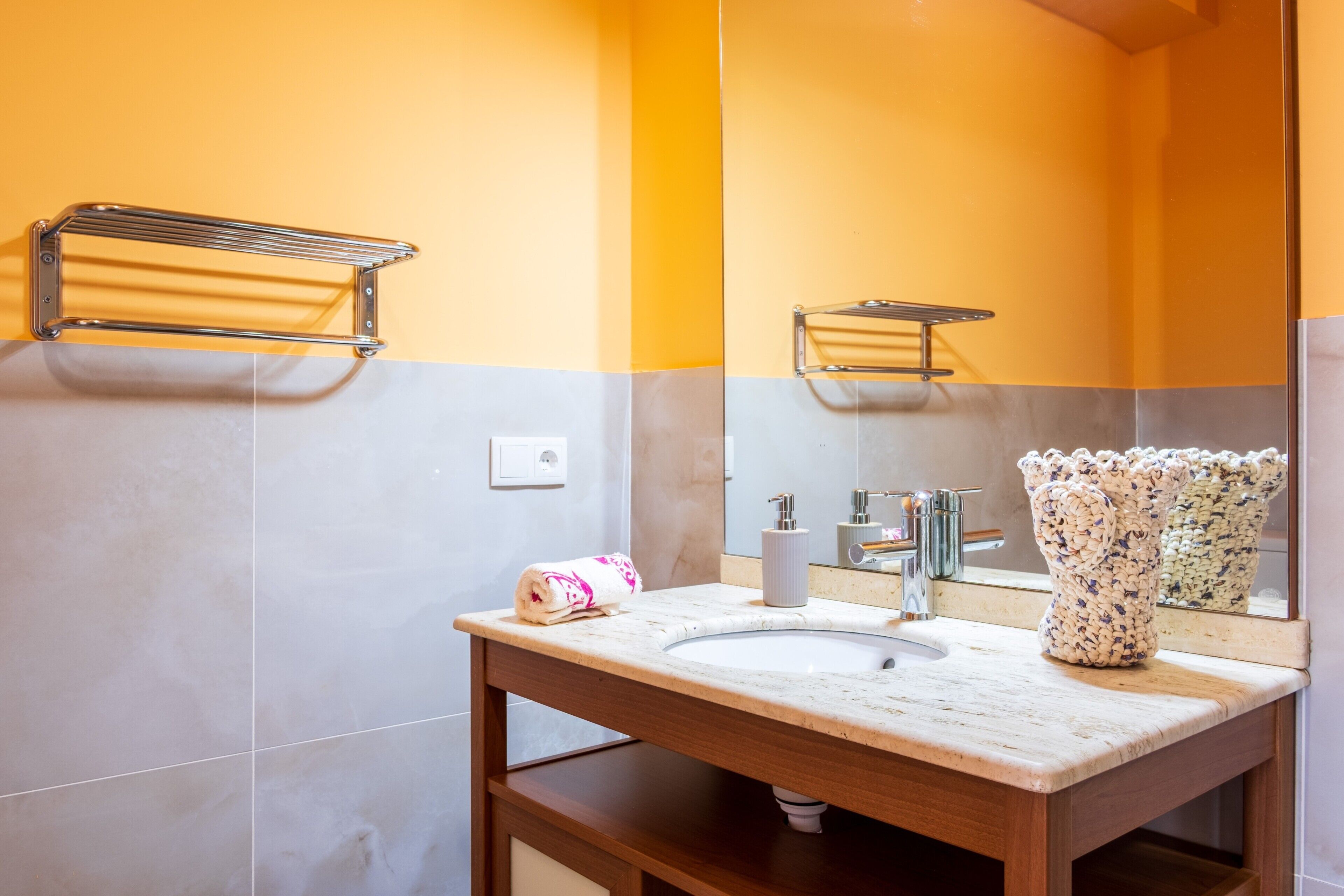 Une salle de bain avec un lavabo en marbre, une serviette, un miroir et un porte-serviettes.