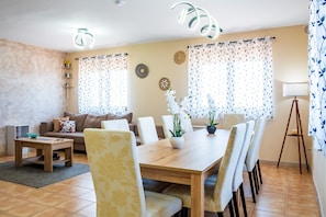 A dining area with a wooden table and chairs, a sofa, and a lamp.