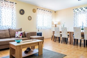 A living room with a sofa, coffee table, dining table with chairs, and decorative wall art.