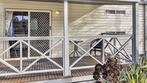 A covered outdoor area with a wooden deck, a metal railing, and a table with chairs. - 2 Bedroom Budget Villa (Metung)