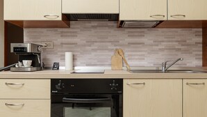 Eine moderne Küche mit Holzausstattung, einem Einbauofen, einer Kaffeemaschine und einem Spülbecken.