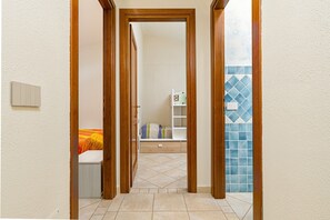 A hallway with wooden doors leading to a room with a bed and a shelf. - Holiday Home 'Villetta Lu Lioni' with Private Terrace, Private Garden and Air Conditioning (san teodoro)