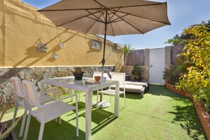 Un patio con una mesa, sillas y una sombrilla.