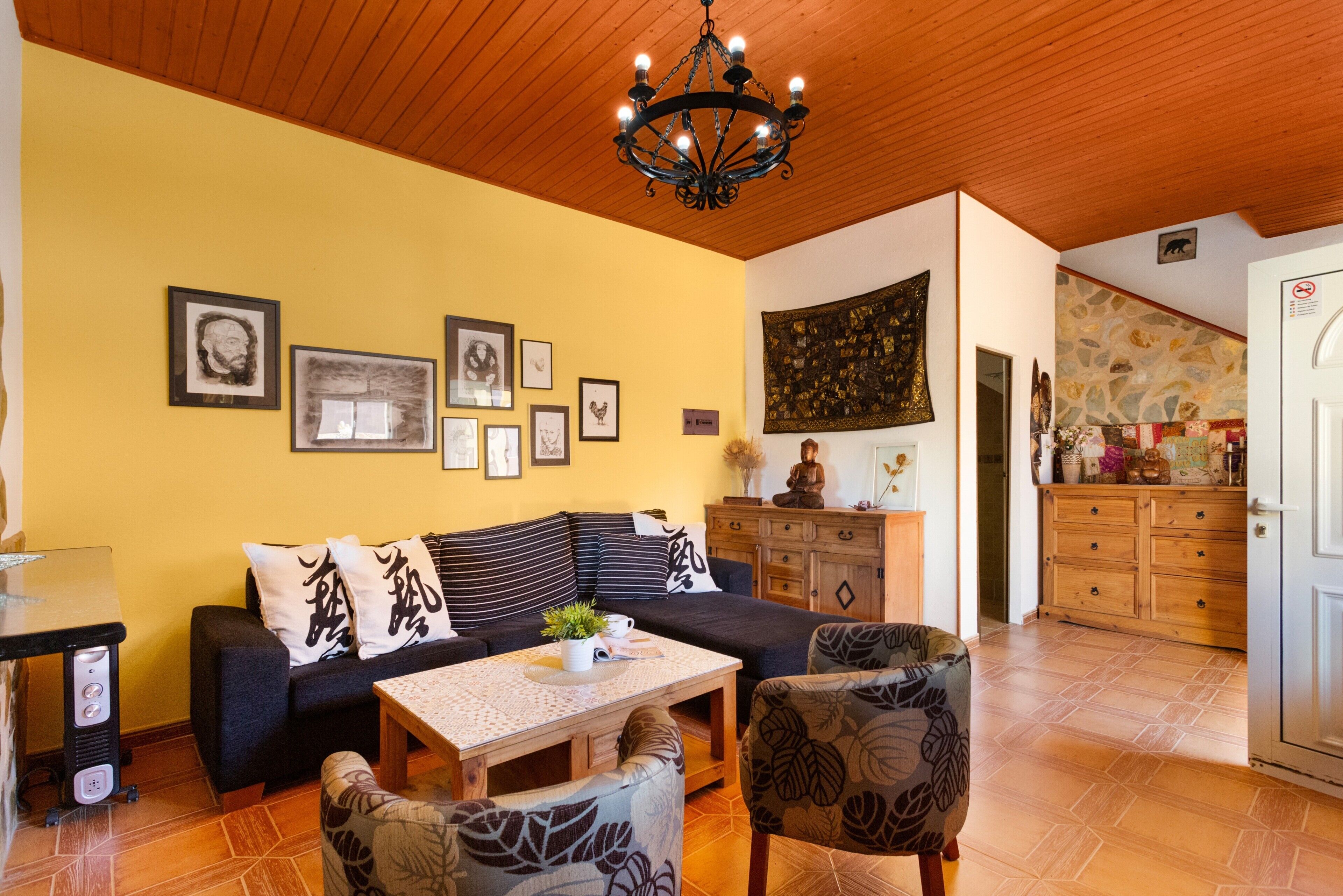 Ein Wohnzimmer mit einer Couch, Sesseln, einem Tisch, einer Kronleuchter und Kunstwerken an den Wänden.