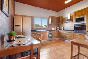 A kitchen with wooden cabinets, a built-in oven, a microwave, and a window. - Vacation Apartment 'Rural Zona Céntrica Isla' with Mountain View, Private Terrace and Wi-Fi (Puerto del Rosario)