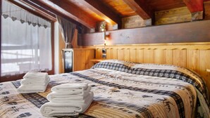 Una habitación con paneles de madera, una cama, un ventanal con cortinas y una pila de toallas.