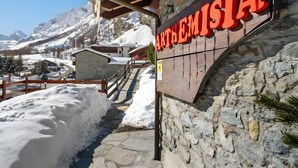 Un sendero cubierto de nieve que lleva a un edificio con un cartel que dice 'ARTHEMISIA'.