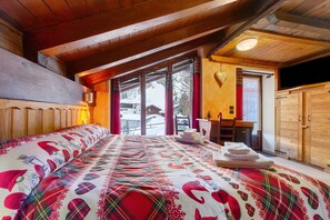 Um quarto aconchegante com uma cama grande, uma escrivaninha de madeira e uma porta de correr para uma varanda.