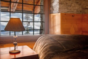 A bed with a wooden headboard, a bedside lamp, and a window with a view of the outside.