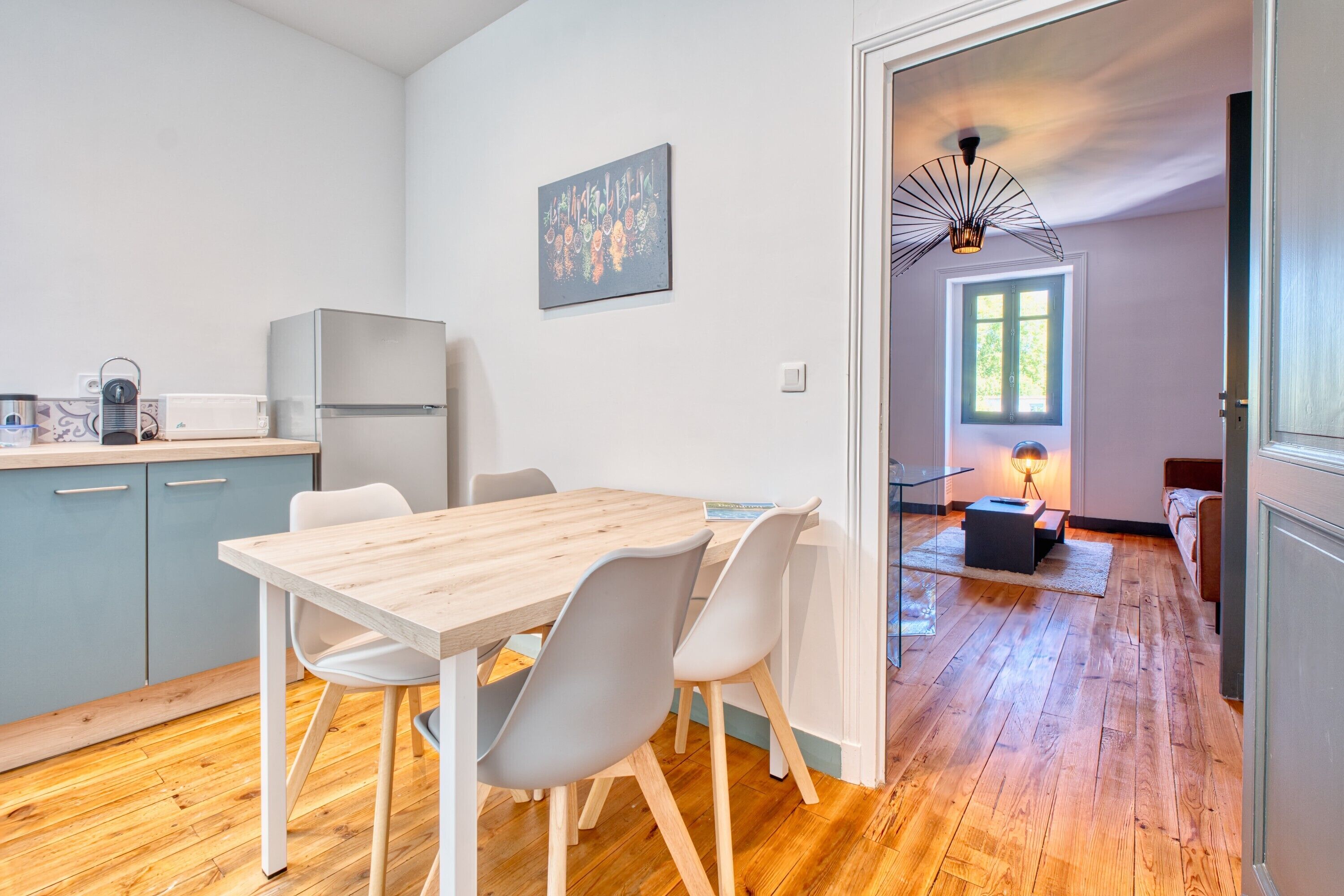 A modern kitchen with a wooden table and chairs, a refrigerator, and a dining area.