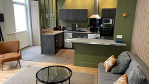Une cuisine moderne dotée d’un îlot central, d’appareils électroménagers intégrés et d’un coin repas avec une table en verre.