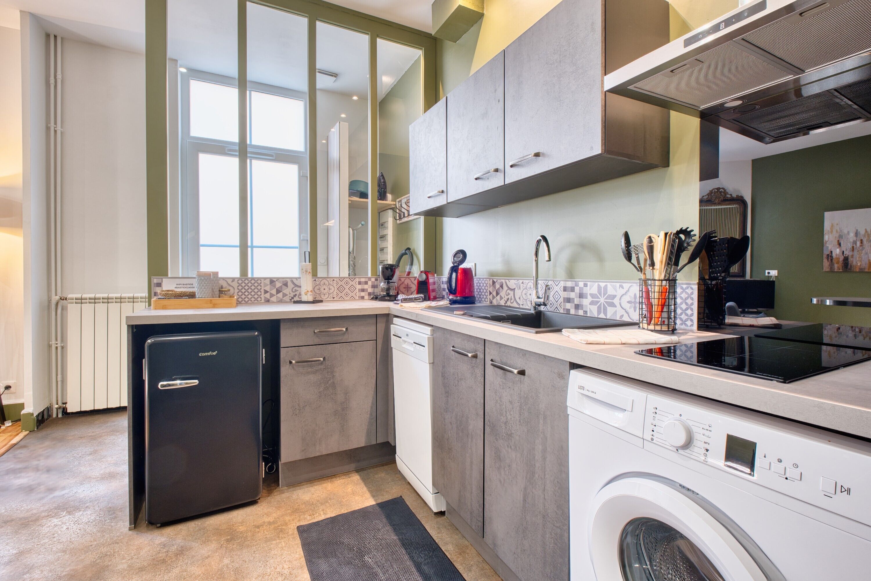 A compact kitchen with a dishwasher, washing machine, and a small refrigerator.