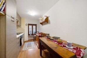 A compact kitchen with a dining area, wooden cabinets, and a window. - Apartment 'L'archetto Valle D'Aosta' with Mountain View and Wi-Fi (La Salle)