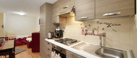 A modern kitchen with wooden cabinets, a gas stove, a coffee maker, and a sink.