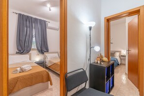Une chambre d’hôtel avec deux lits, un bureau avec une lampe et une armoire.