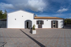 Un bâtiment blanc avec un toit en tuiles, une porte et une fenêtre avec des volets.