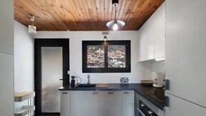A compact kitchen with a wooden ceiling, a window with a view, and built-in appliances. -  Le Carlit – Apartment in Les Angles with mountain view, cosy and functional (Les Angles)