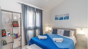 Un dormitorio ordenado con una cama, una estantería y una ventana con cortinas.