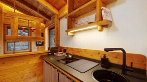 A wooden cabin interior with a kitchen area, including a sink, kettle, and wooden shelves. - Studio 'Con Idromassaggio' with Mountain View, Balcony and Wi-Fi (Aymavilles)