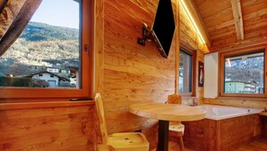 A wooden interior with a round table, wooden chair, and a bathtub. - Studio 'Con Idromassaggio' with Mountain View, Balcony and Wi-Fi (Aymavilles)
