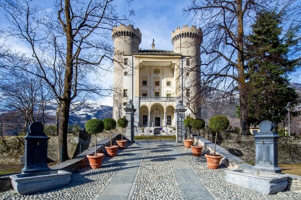 A castle with two towers, a central entrance, and a paved pathway leading to it.
