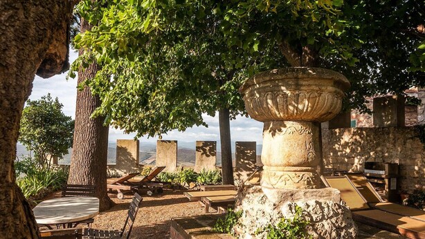 Una fuente de piedra, bancos de madera y vista al mar.