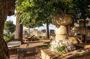 A stone fountain, wooden benches, and a view of the sea.