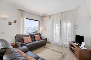 Una sala de estar con un sofá, un televisor y un mueble de madera.