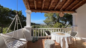 Une terrasse dotée d’un plafond en bois, de rampes blanches et offrant une vue sur le paysage.
