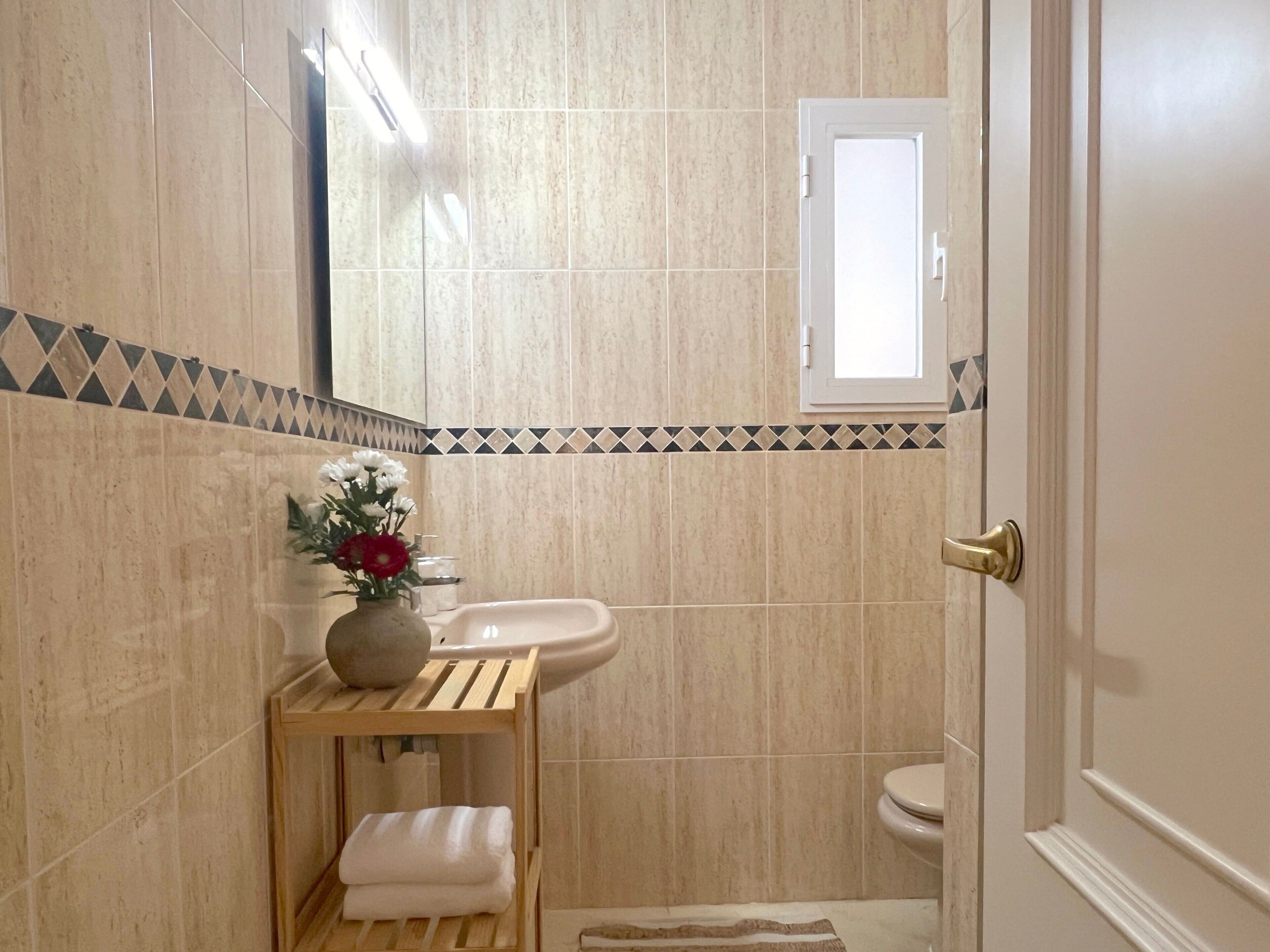 Un baño con lavamanos, inodoro y espejo.