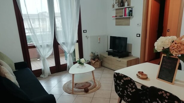 Una sala de estar con sofá, mesa de centro, televisor y comedor con mesa y sillas.