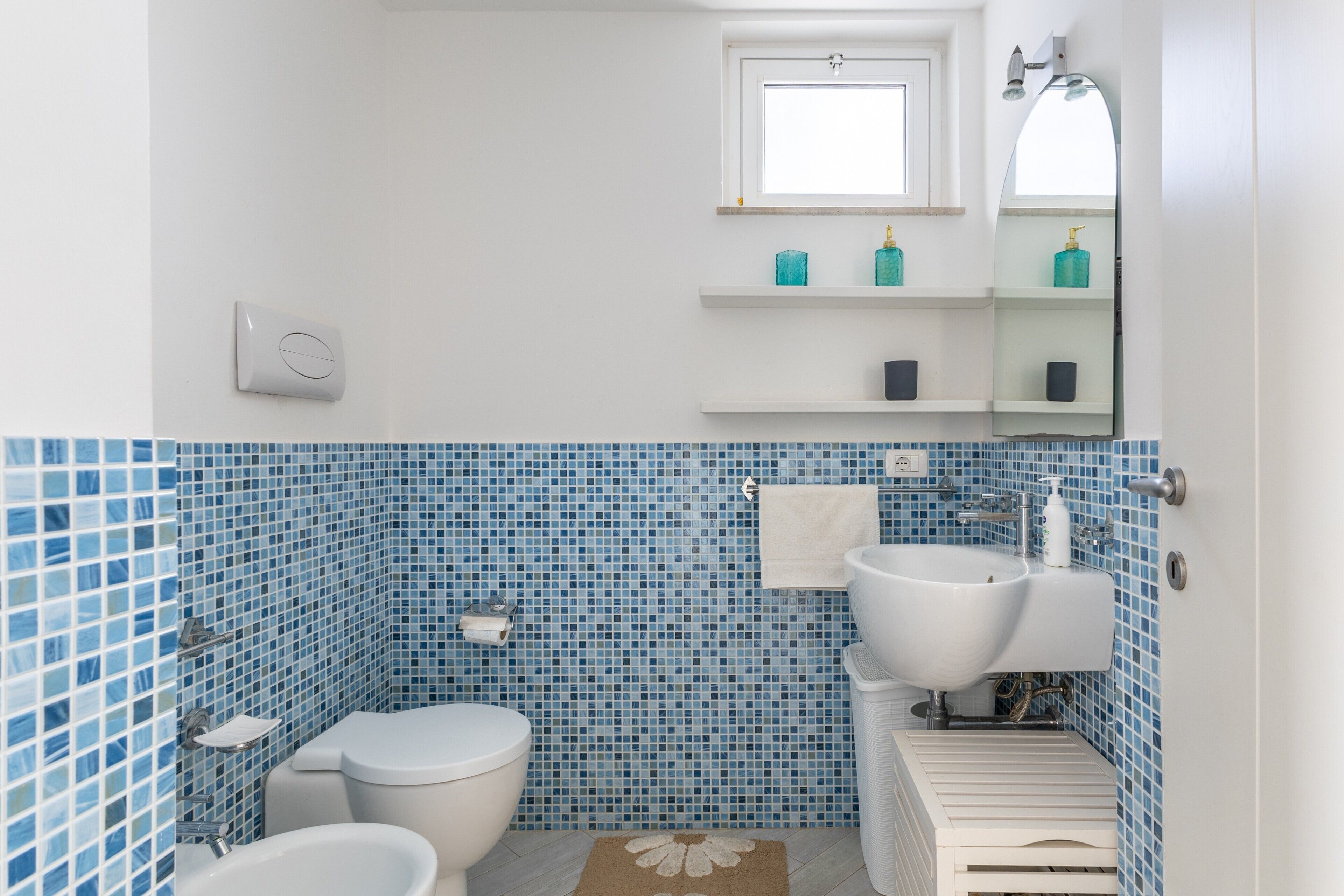 A bathroom with a toilet, bidet, sink, and a mirror above the sink.