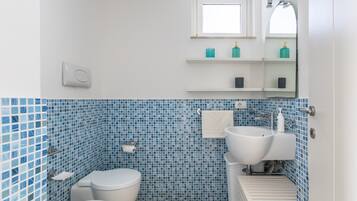 A bathroom with a toilet, bidet, sink, and a mirror above the sink.