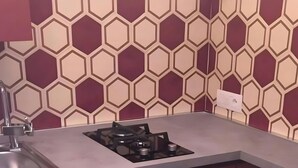 Une cuisine avec un sol à motifs hexagonaux, une cuisinière à gaz et des meubles de couleur sombre.