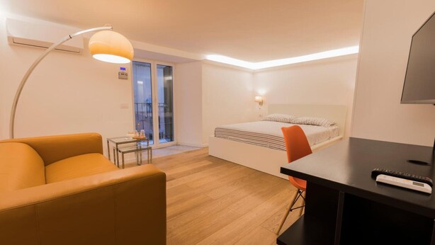Une chambre d’hôtel avec un lit, un bureau, une chaise, une lampe et un téléviseur.