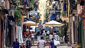 Une rue étroite bordée d’immeubles à étages, de balcons et d’espaces aménagés pour s’asseoir à l’extérieur.