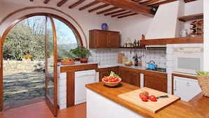 A kitchen with wooden cabinets, a white dishwasher, a wooden countertop, and a view through an arched doorway. - Holiday Home 'Chianti Loft' with Mountain View, Wi-Fi and Air Conditioning (Greve in Chianti)