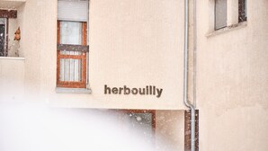 A building with a sign that reads 'herbouilly' and a window with a wooden frame.