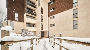 A snow-covered pathway leading to a building with multiple windows and balconies.