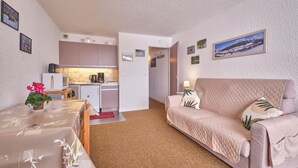 A compact living space with a kitchenette, a sofa, and a dining area.