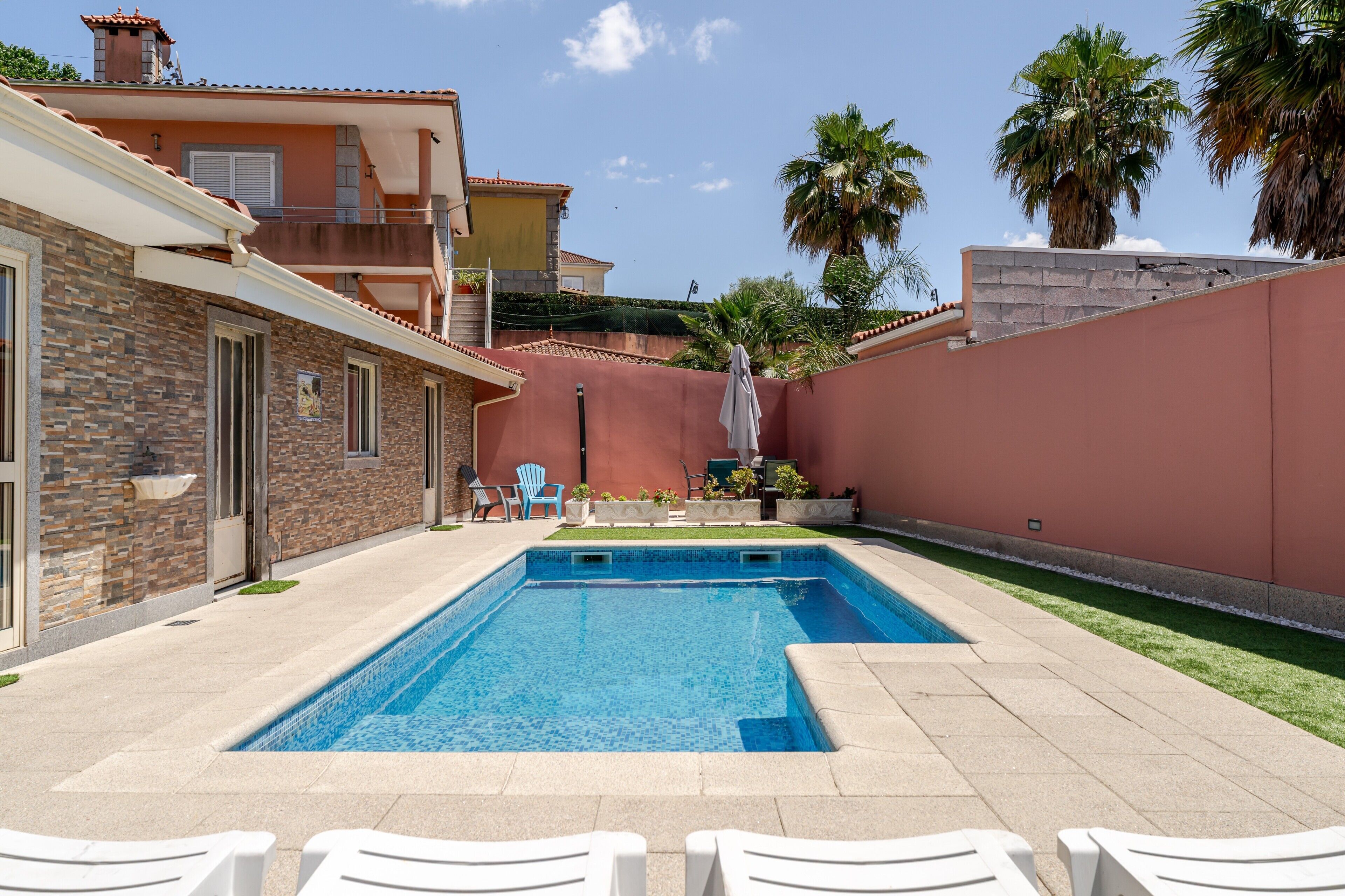 Una piscina con lettini, un edificio in pietra e palme.
