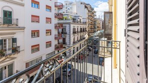 Un edificio de varios pisos con balcones, vista a la calle y automóviles estacionados.
