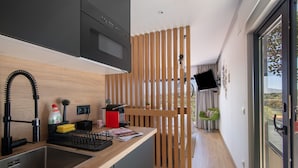 Una cocina moderna con un lavamanos integrado, un separador de madera, un televisor montado en la pared y vistas al exterior.