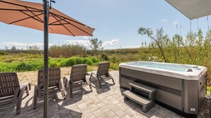 An outdoor patio with a hot tub, four chairs, and a large umbrella. - Cozy home in Povljana with WiFi (Povljana)
