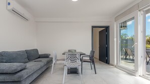 A modern living room with a grey sofa, a dining table with chairs, and a sliding glass door leading to an outdoor area. - Cozy home in Povljana with WiFi (Povljana)