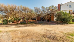 A rustic outdoor seating area with wooden benches and tables, surrounded by trees and a dirt path. - Cozy home in Povljana with WiFi (Povljana)