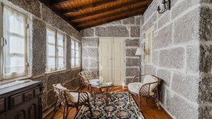A stone-walled room with a wooden ceiling, a dining table with chairs, a white door, and a window with curtains. - Holiday Home 'Tilde' with Mountain View, Wi-Fi and Air Conditioning (Fafe)