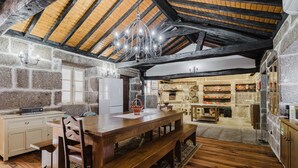 A rustic kitchen with a wooden table, bench, stone walls, and a stone fireplace. - Holiday Home 'Tilde' with Mountain View, Wi-Fi and Air Conditioning (Fafe)