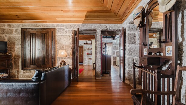 A stone-walled room with a wooden floor, a leather sofa, a wooden chair, and a television on a wooden stand. - Holiday Home 'Tilde' with Mountain View, Wi-Fi and Air Conditioning (Fafe)